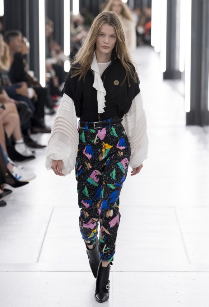 стройная девушка с цветастых брюках, белой блузе с пышными рукавами и черным жилетом - модные идеи с модных показов весна-лето 2019